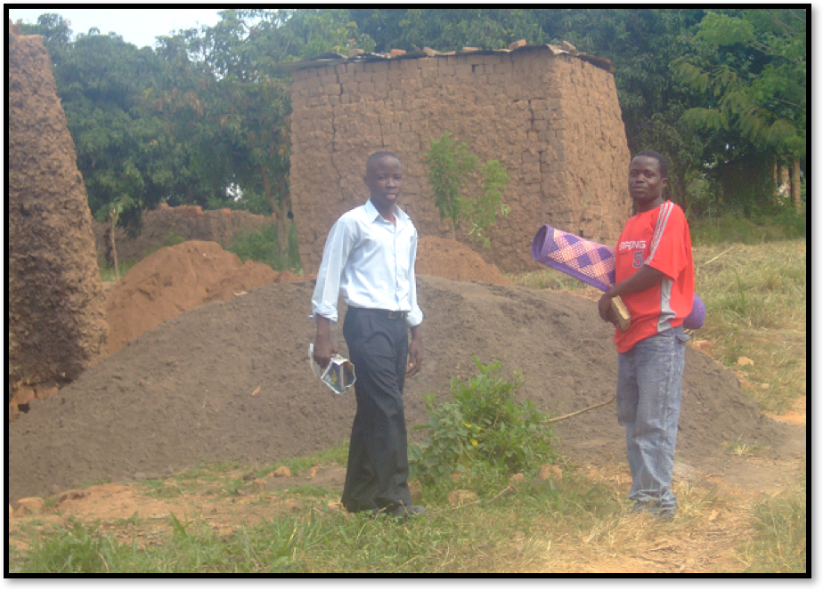 To reduce on costs, bricks were made and fired at the site. These are two piles of bricks ready for use. A hip of Sand bought and ready for construction work to start. On the left is James Kaliisa Musaasizi and Seruwagi Israel on the right.